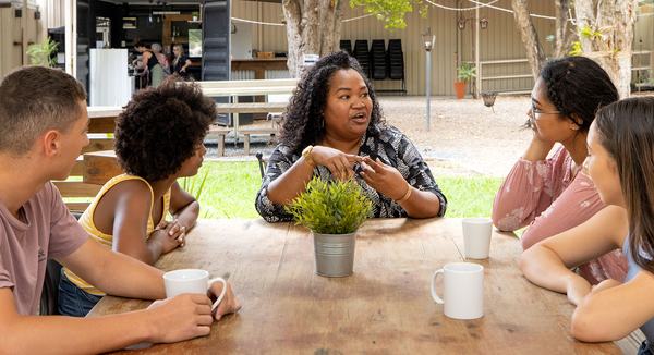 A small group talks together around a cafe table.